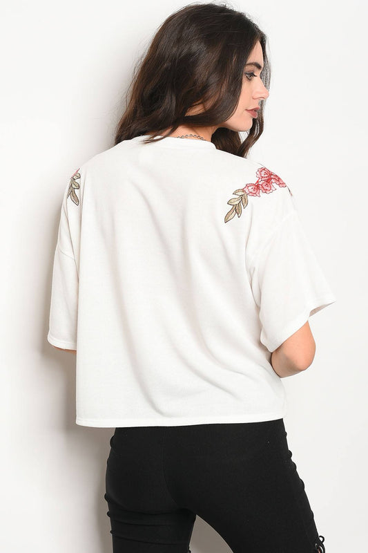 Ladies fashion 3/4 sleeve light weight knit top with a crew neckline and floral patch details